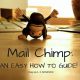 a mail chimp monkey upside down on a desk next to computer