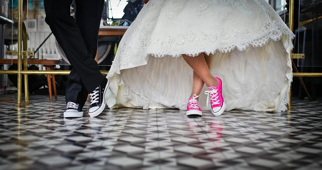 bride a groom's feet wearing black converse and pink converse with suit and white dress