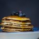 a stack of blueberry pancakes in a bowl with syrup on