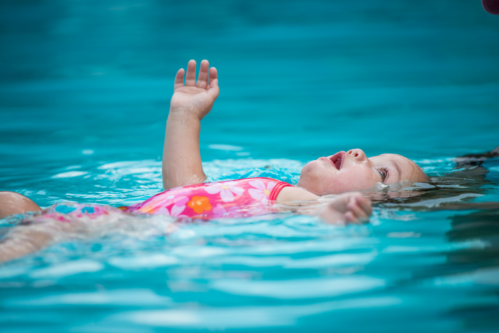 baby girl floating in a swimming pool in a pink costume