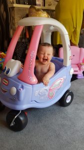 alyssa smiling in a pink and purple toy car