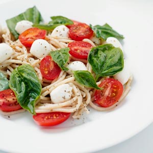 spaghetti with basil leaves halves of baby tomatoes and green basil leaves