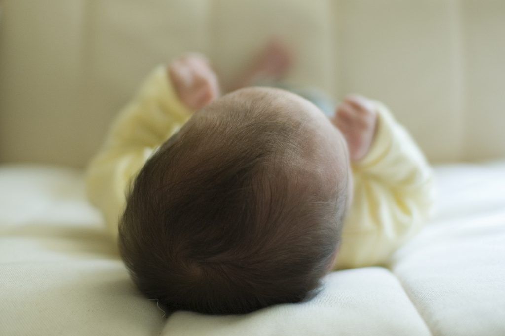 dark haired baby head lying down away from camera