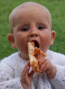 A baby eating a slice of pizza