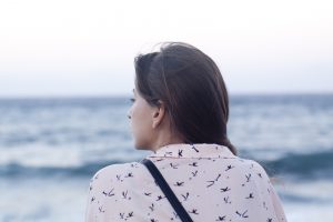 woman looking out at the sea. facing away from the camera