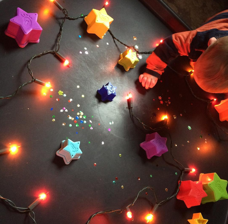 little boy on a black plastic mat with stars, lights and sequins on it