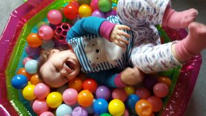 alyssa lying in a ball pit legs in the air