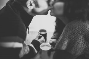 man and woman kissing over coffee