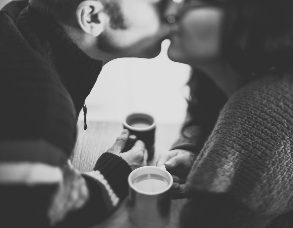 man and woman kissing over coffee