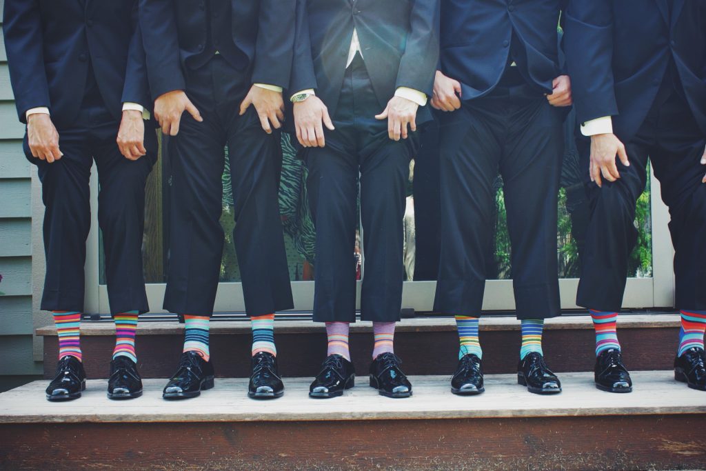 a row of men lifting trouser legs so you can see their socks