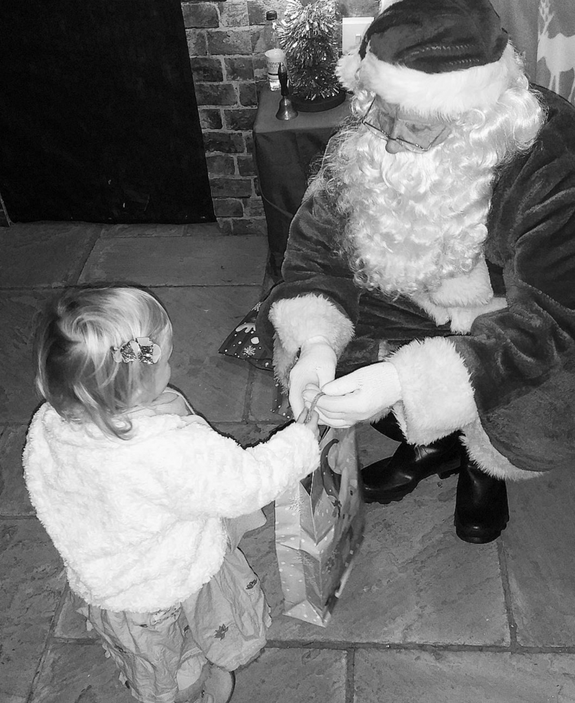 little girl receiving a bag or present from father christmas