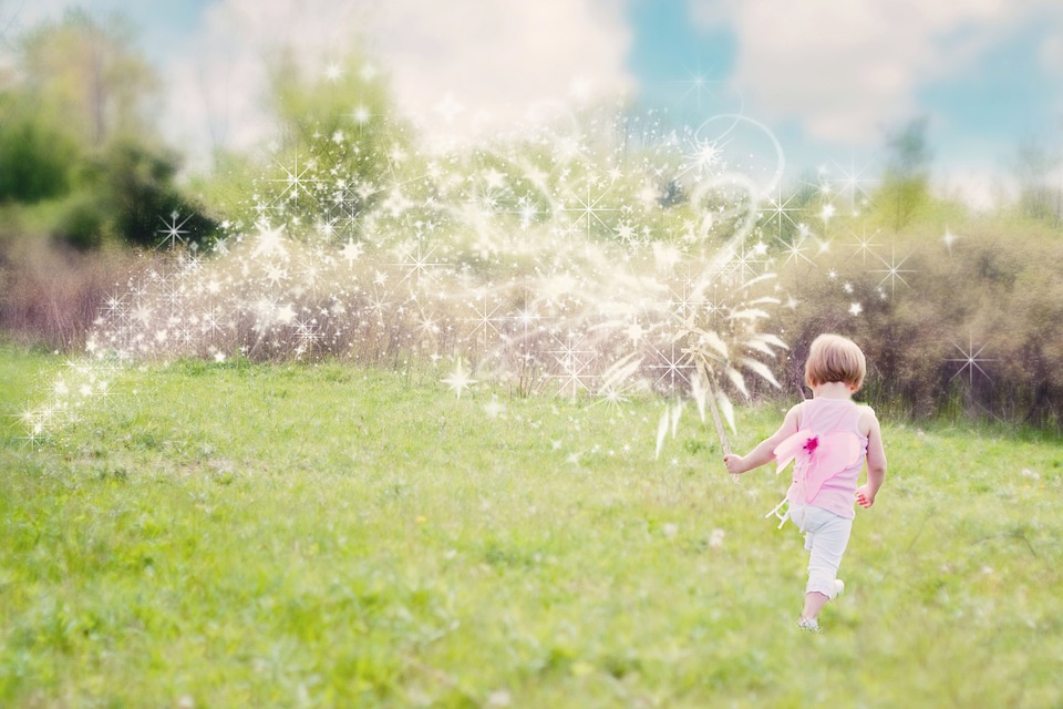 little girl walking in a field with magical sparkles behind her