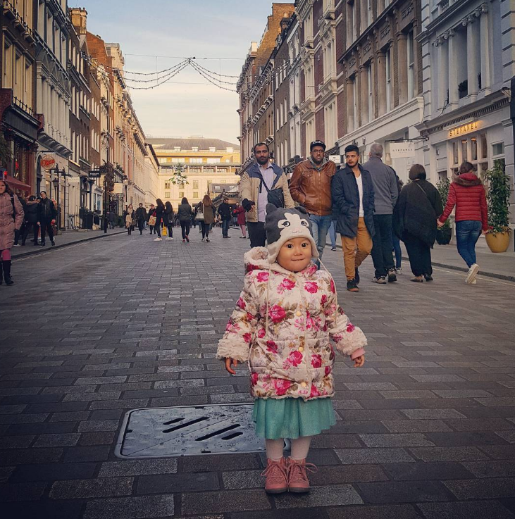 little girl on a busy high street in a blue skirt and pink tights boots and coat