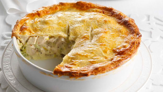 a chicken and mushroom pie with a segment missing in a white dish