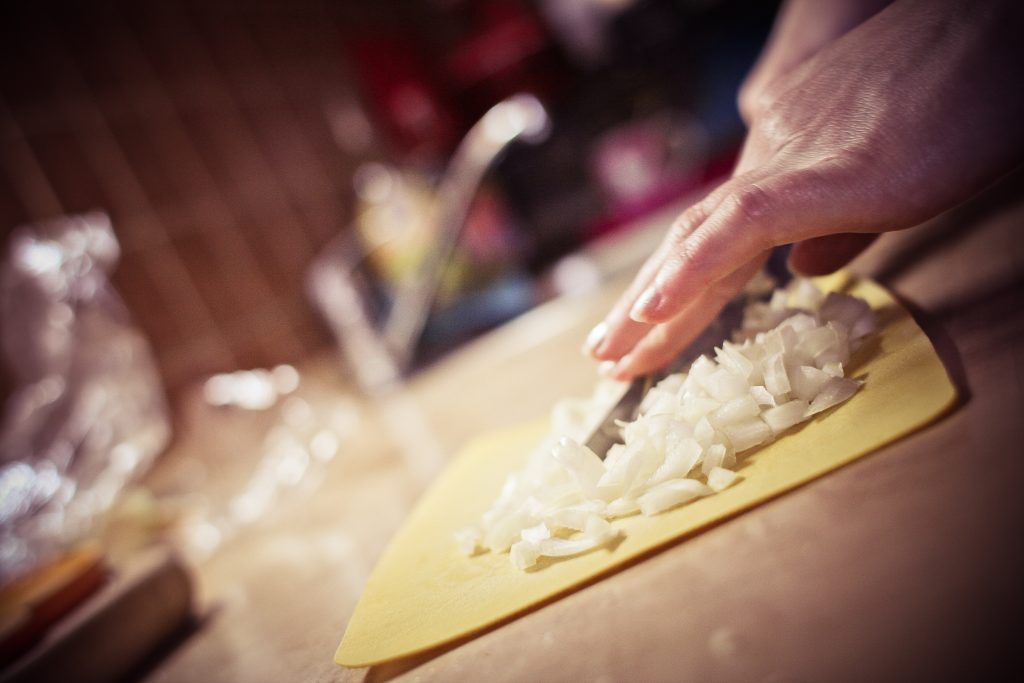 slicing onions on a chopping board in a kitchen
