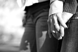 a couple holding hands the womans is on top so you can see the ring. black and white