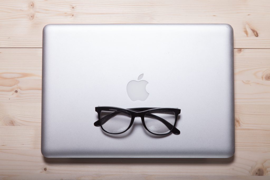 closed macbook with a pair of black framed glasses on top