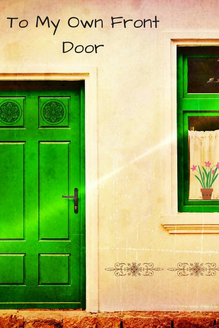 a yellow wash building with a bright green front door and framed window with curtains