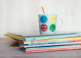 a stack of childrens books with a cup and straw on top