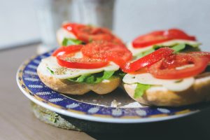 a plate with 4 open sandwiches with lettuce cheese and tomato on