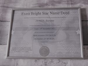 certificate of ownership of the star with all the details in a silver frame on a white wooden background