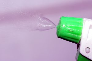 a green nozzle with spray coming out of it