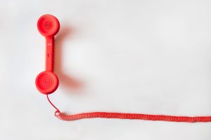 white background with a red long cord telephone