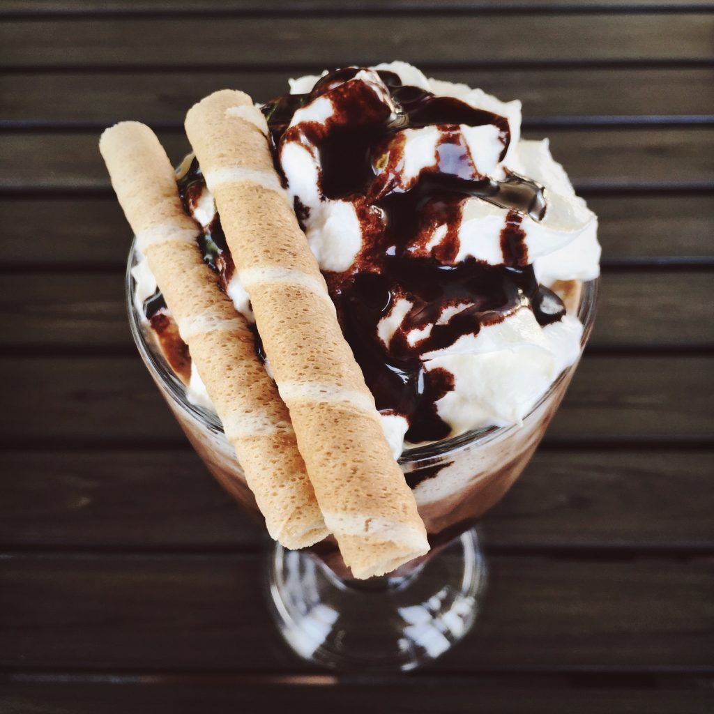 a top shot of a bowl of icecream with wafers and chocolate sauce