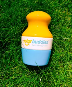 a yellow white and blue plastic solar buddies applicator with the lid on sat on grass