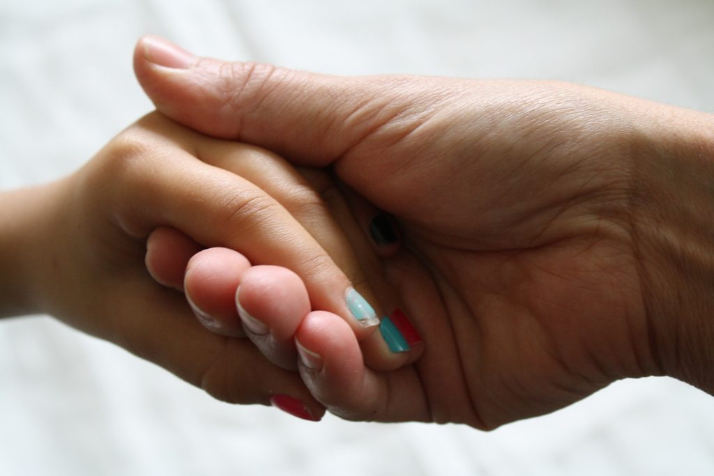 two hands holding. one with chipped aqua nail varnish on