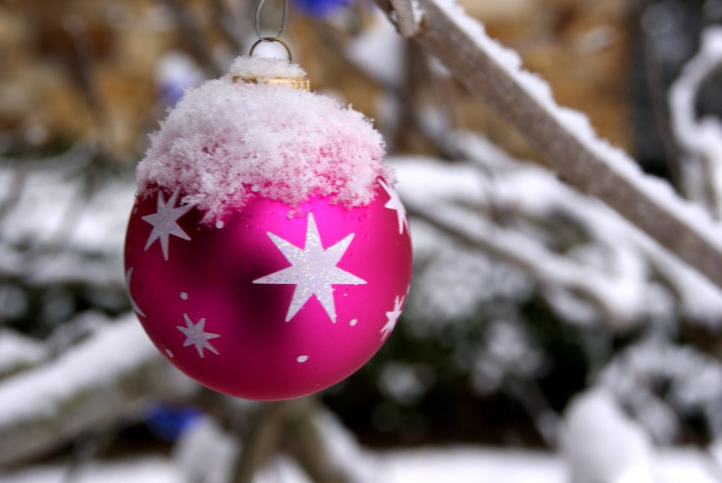 pink bauble hanging from a snowy branch