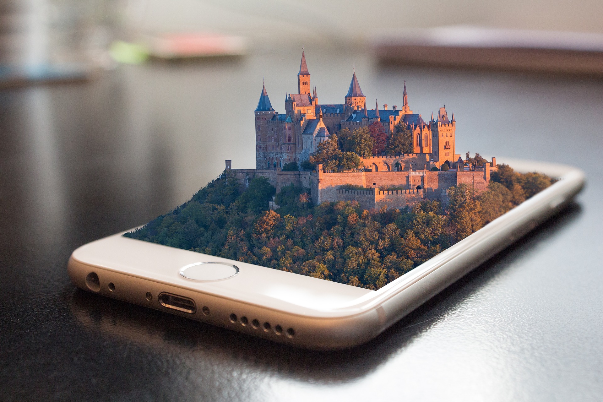 a white mobile phone on a table with a picture of a castle coming out of it that looks 4d