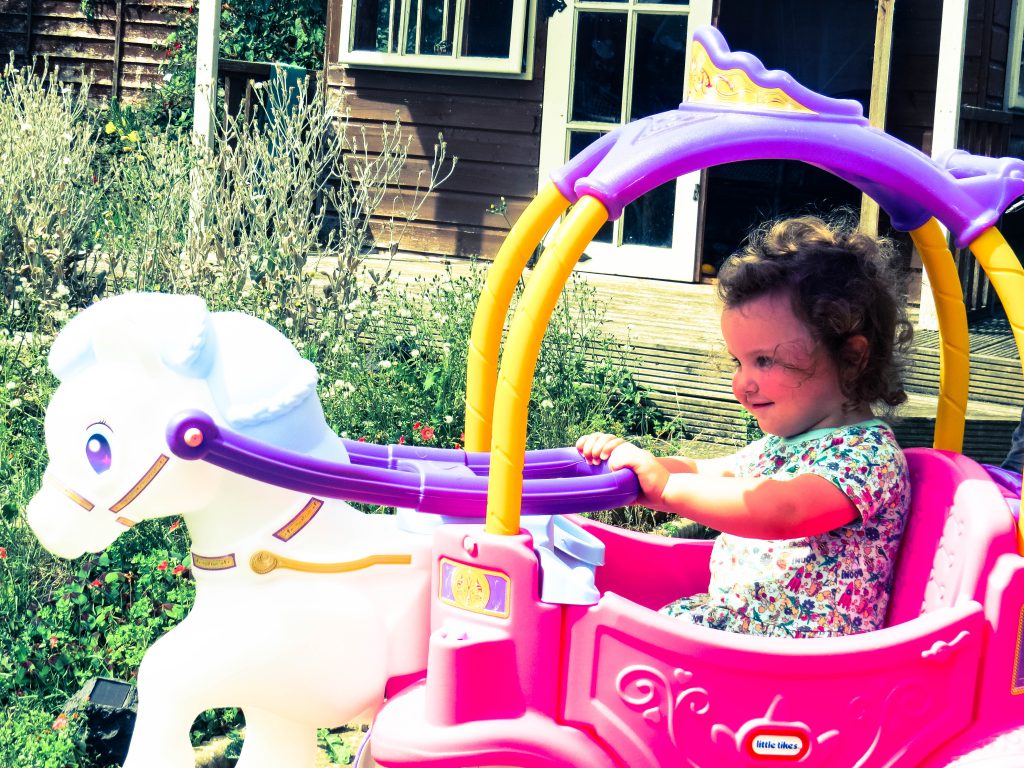 alyssa in a pink and purple plastic horse and carriage with a white horse