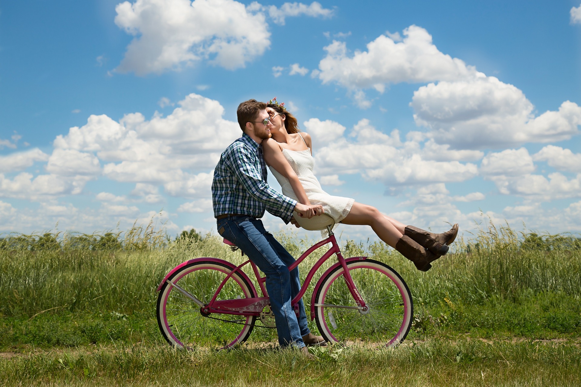 a man riding a bicycle with a woman on the handle bars on a blue sky day