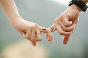 two fingers both with an anchor tattoed on holding each others finger