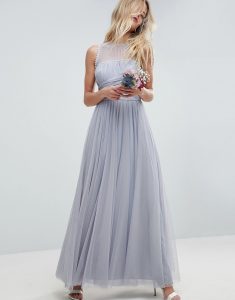 a blonde girl stood in a pale blue tulle dress holding flowers