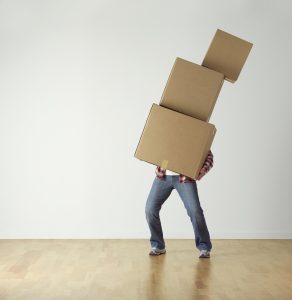 a man holding 3 boxes stacked up over him about to fall
