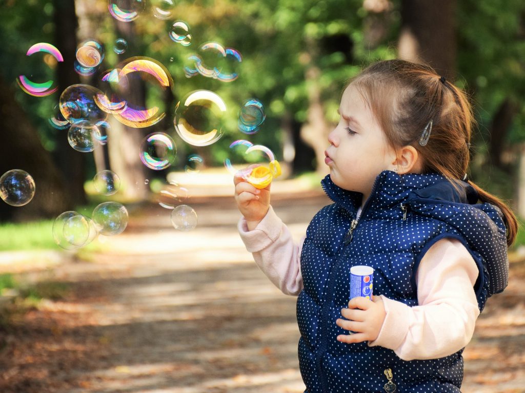 a little girl blowing bubbles in the woods