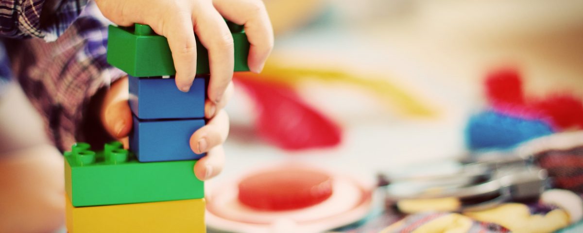 a childs hand playing with colourful building blocks