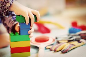 a childs hand playing with colourful building blocks