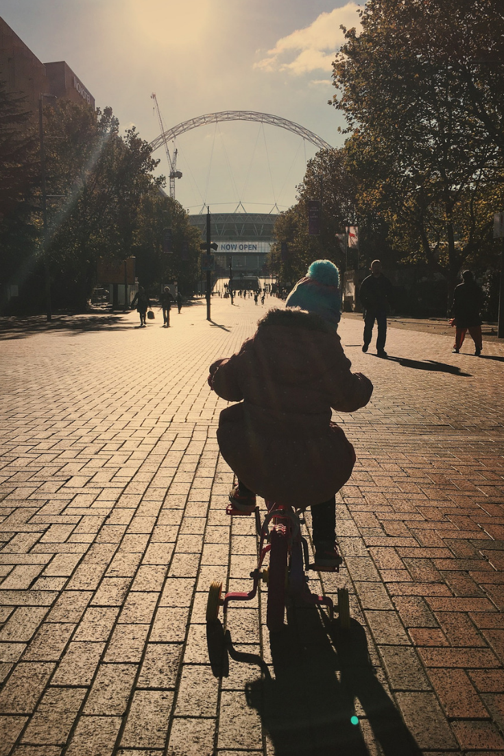 a child riding a bike down a street into the sun