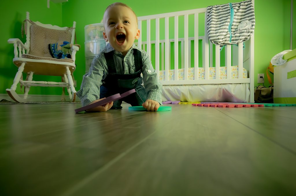 a toddler crawling on the floor smiling at the camera 