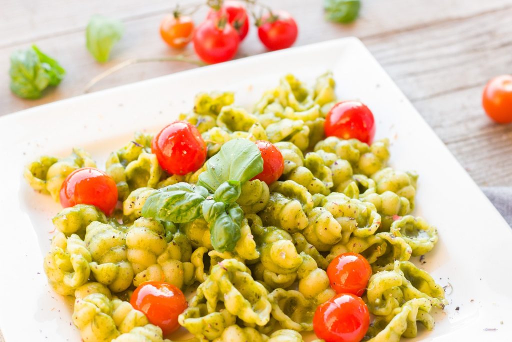 a plate of avocado basil pasta with tomatoes