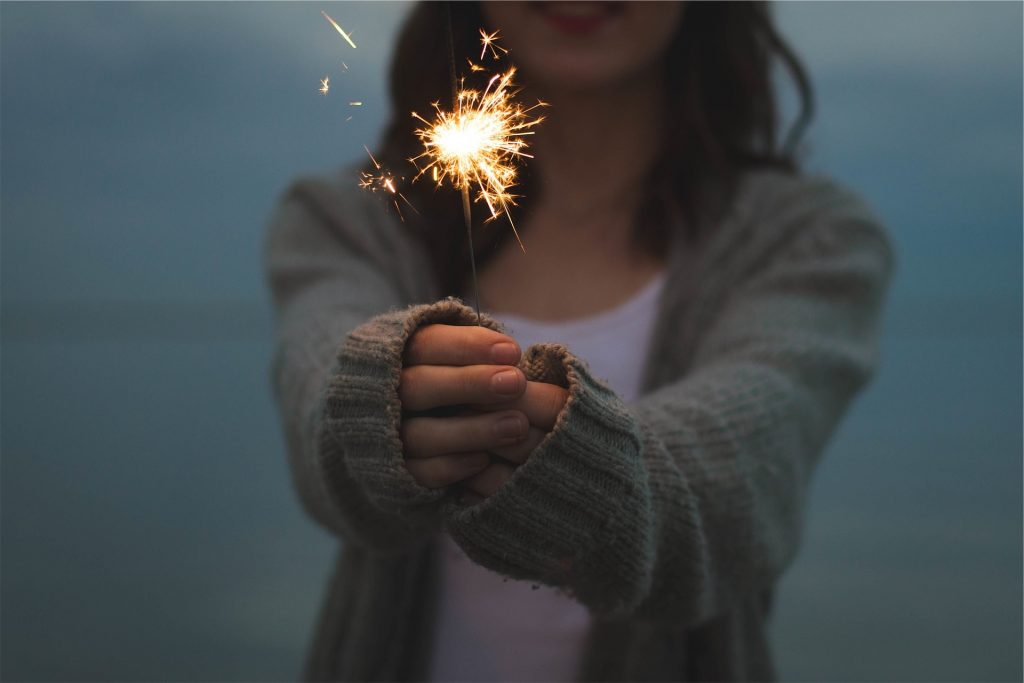 a woman wearing a cardigan holding out a sparkler