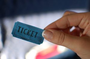 a woman's hand holding a blue ticket stub that says ticket
