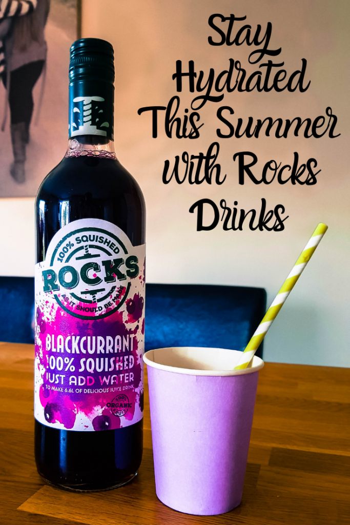bottle of rocks blackcurrant drink next to a paper cup and straw