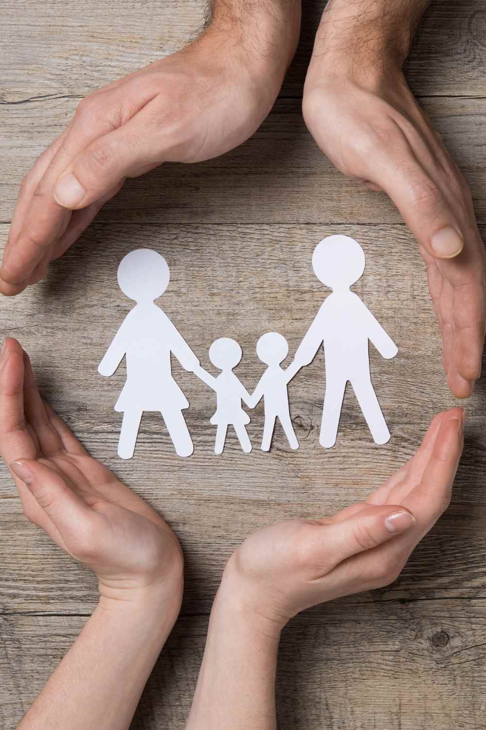 hands around paper cut outs of a family to show care