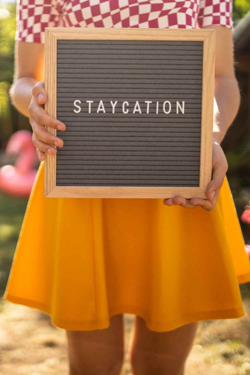 a sign that says staycation held by a woman