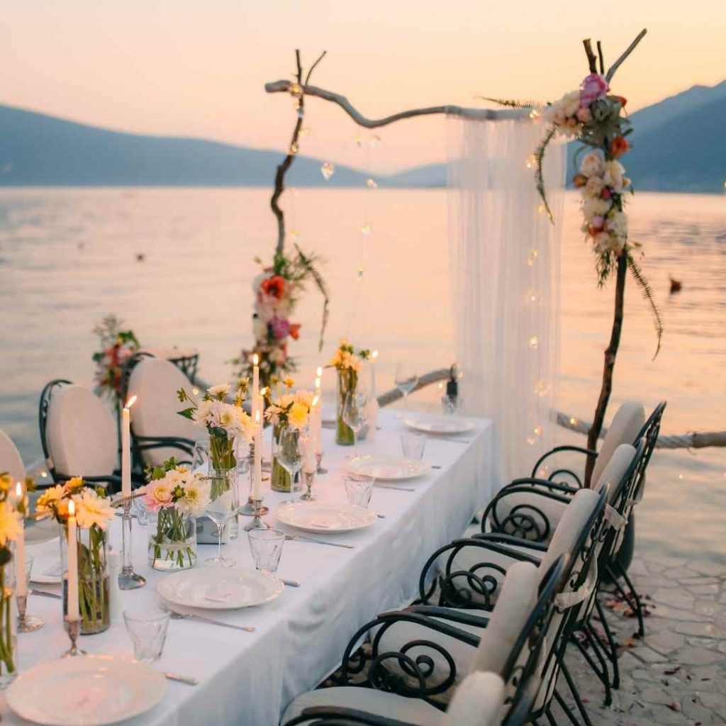 finding the perfect venue for a wedding - table and chairs and arch on beach at sunset