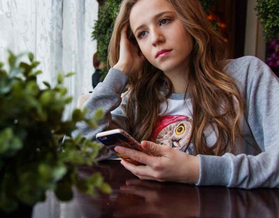 teenage girl with a phone looking out of a window